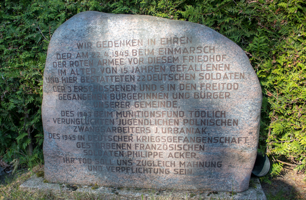 WIR GEDENKEN IN EHREN DER AM 22.4.1945BEIM EINMARSCH DER ROTEN ARMEE VOR DIESEM FRIEDHOF IM ALTER VON 15 JAHRENEN GEFALLENEN UND HIER BESTATTETEN 22 DEUTSCHEN SOLDATEN, DER § ERSCHOSSENEN UND 5 IN DEN FREITOD GEGANGENEN BÜRGERINNEN UND BÜRGER UNSERER GEMEINDE, DES 1943 BEIM MUNITIONSFUND TÖDLICH VERUNGLÜCKTEN JUGENDLICHEN POLNISCHEN ZWANGSARBEITERS J. URBANEK, DES 1945 IN DEUTSCHER KREIGSGEFANGENSCHAFT GESTORBENEN FRANZÖSICHEN SOLDATEN PHILIPPE ACKER, IHR TOD SOLL UNS ZUGLEICH MAHNUNG UND VERPFLICHUNG SEIN.